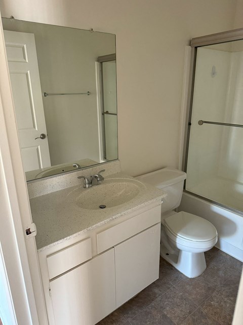 A white bathroom with a sink, toilet and shower.