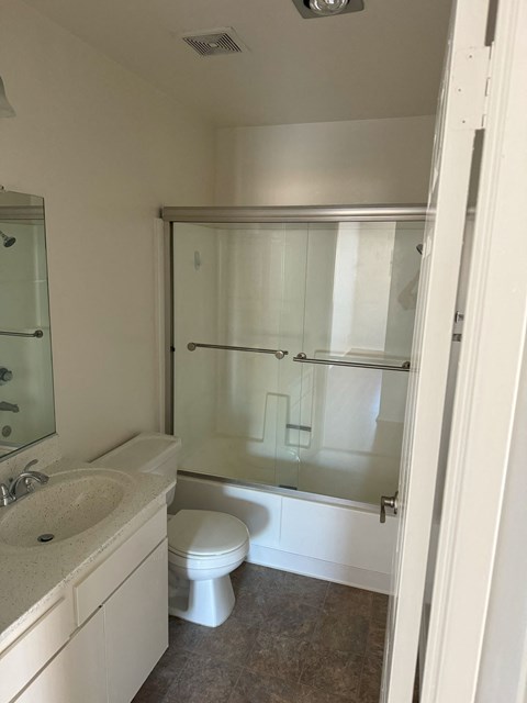 A white bathroom with a toilet, sink, and shower.