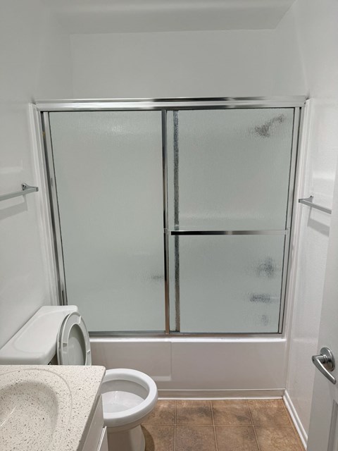 A white toilet sits in a bathroom next to a walk-in shower.