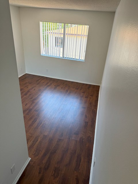 A room with wooden floors and a window with blinds.