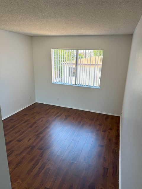 A room with a window and wooden flooring.