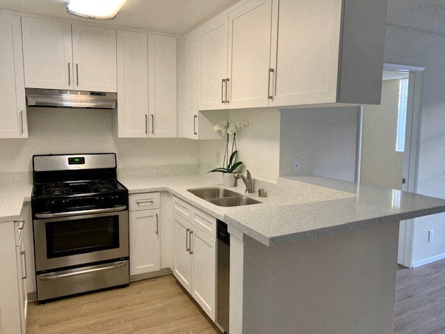 A kitchen with white cabinets and a stainless steel stove.