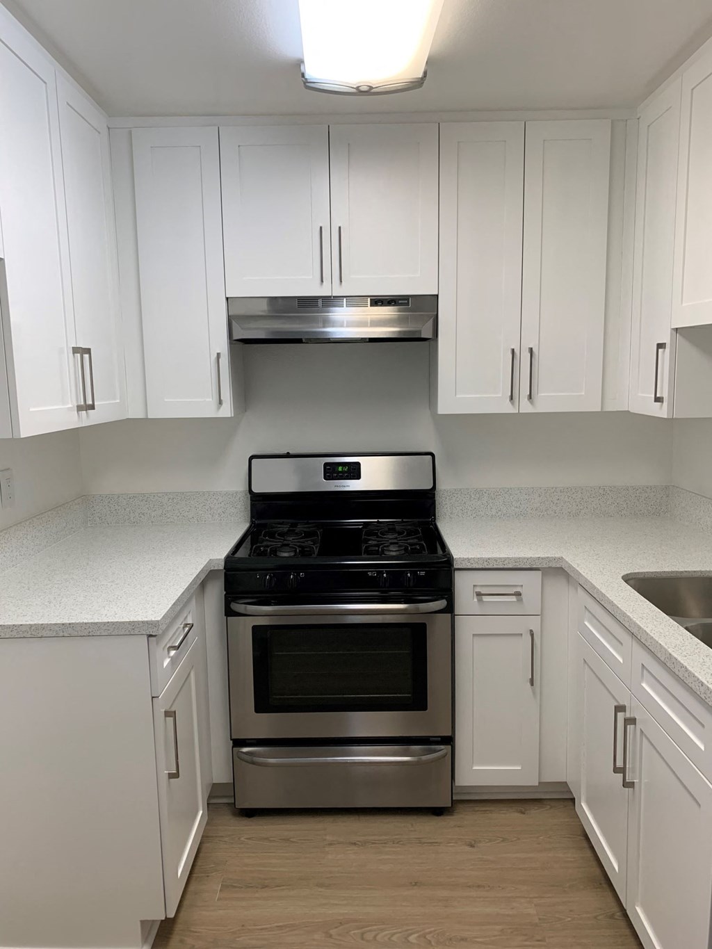 A kitchen with white cabinets and a stainless steel oven.
