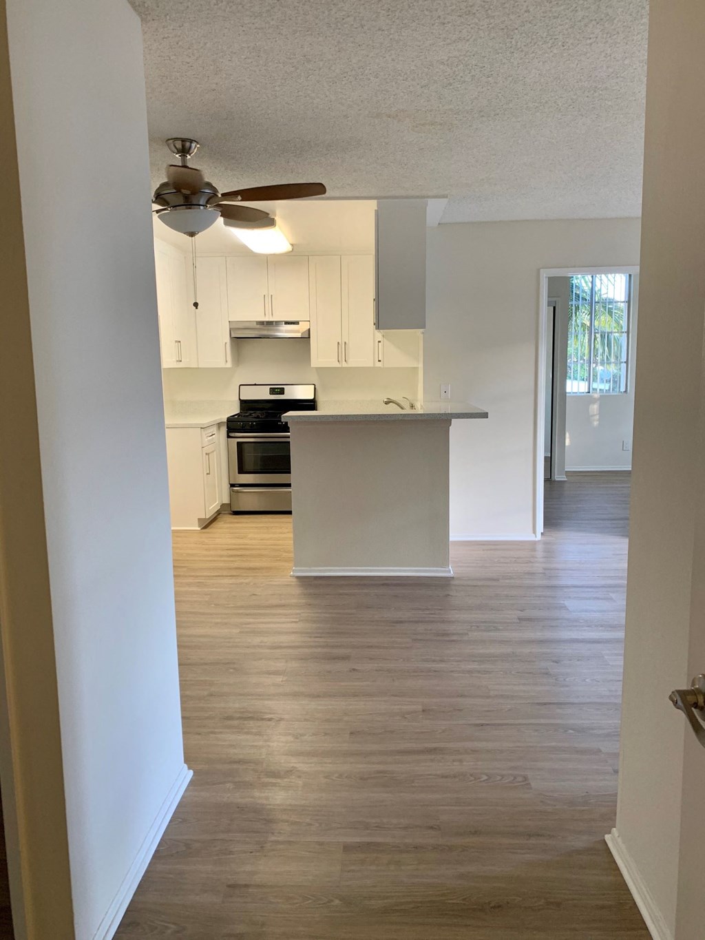 A kitchen with a fan on the ceiling and a stove top oven.