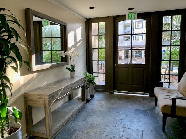 A hallway with a bench, a mirror, and a potted plant.