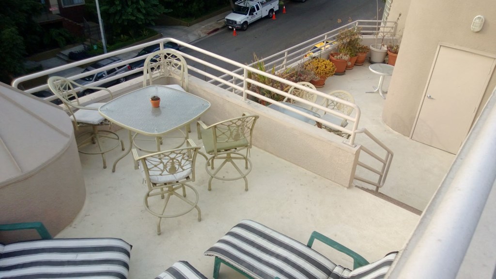 A patio with a table and chairs overlooking a street.