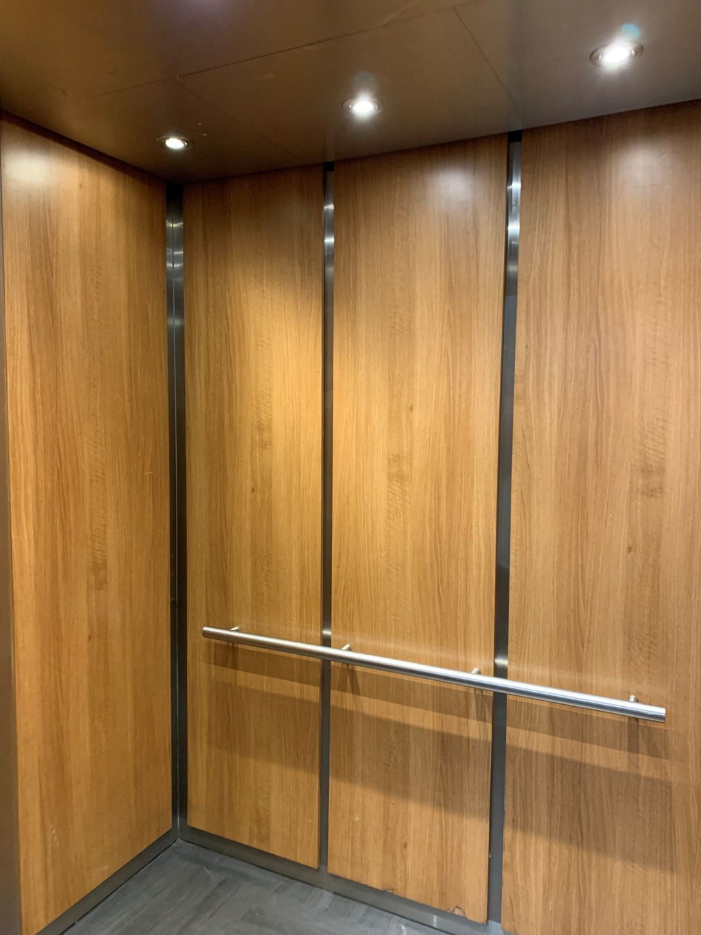 The elevator with wooden walls and a metal bar in the middle.