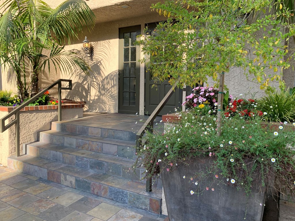 The front entrance of the castle heights apartment with a staircase and a planter with flowers.
