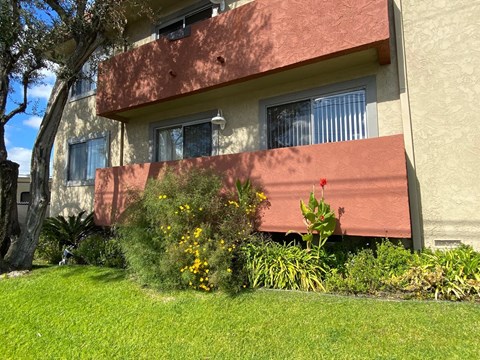 A building with a red awning and a green lawn in front.