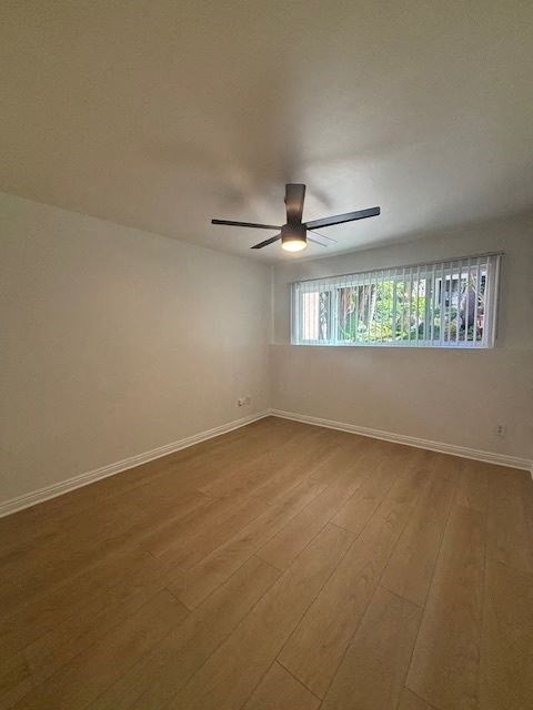 A room with a ceiling fan and a window with blinds.