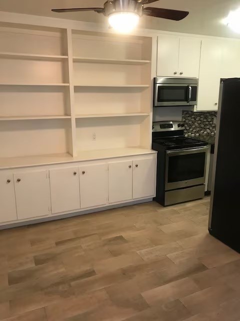 A kitchen with a black refrigerator and white cabinets.