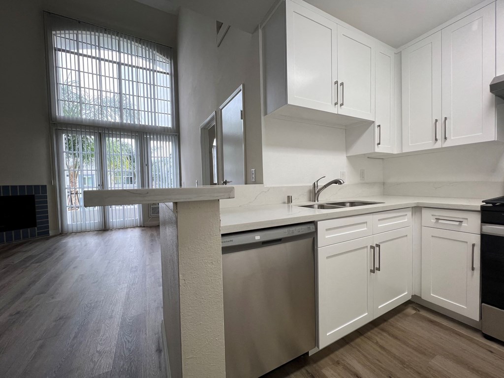 A kitchen with white cabinets and a large window.