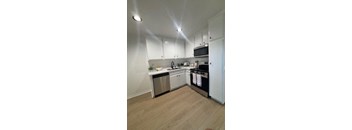 A kitchen with white cabinets and a wooden floor.