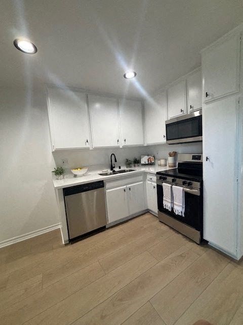 A kitchen with white cabinets and a wooden floor.