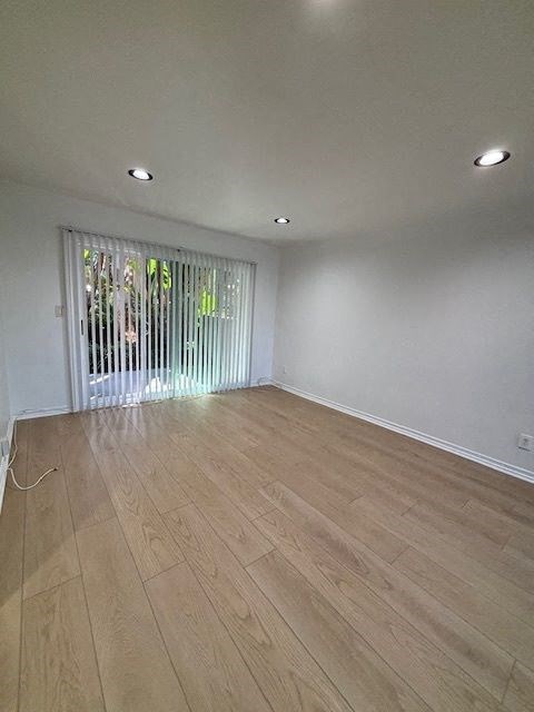 A room with wooden flooring and a window with blinds.
