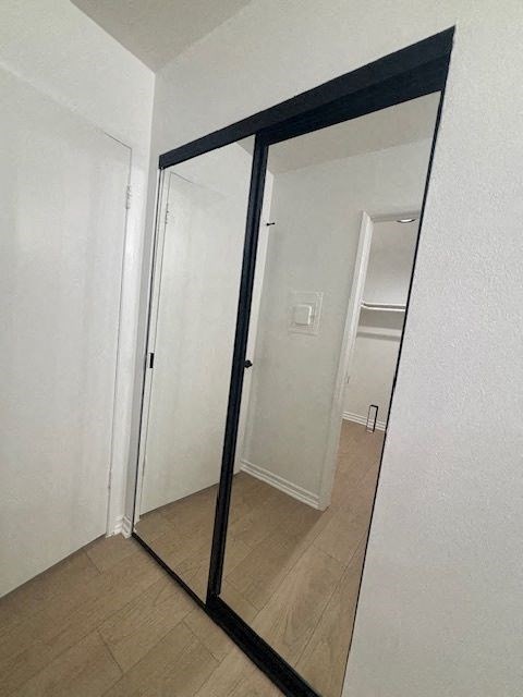 A large mirror with a black frame is leaning against a white wall.
