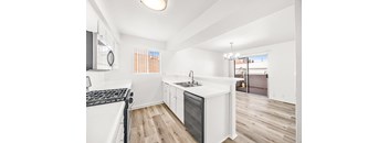 A modern kitchen with white appliances and wooden floors.