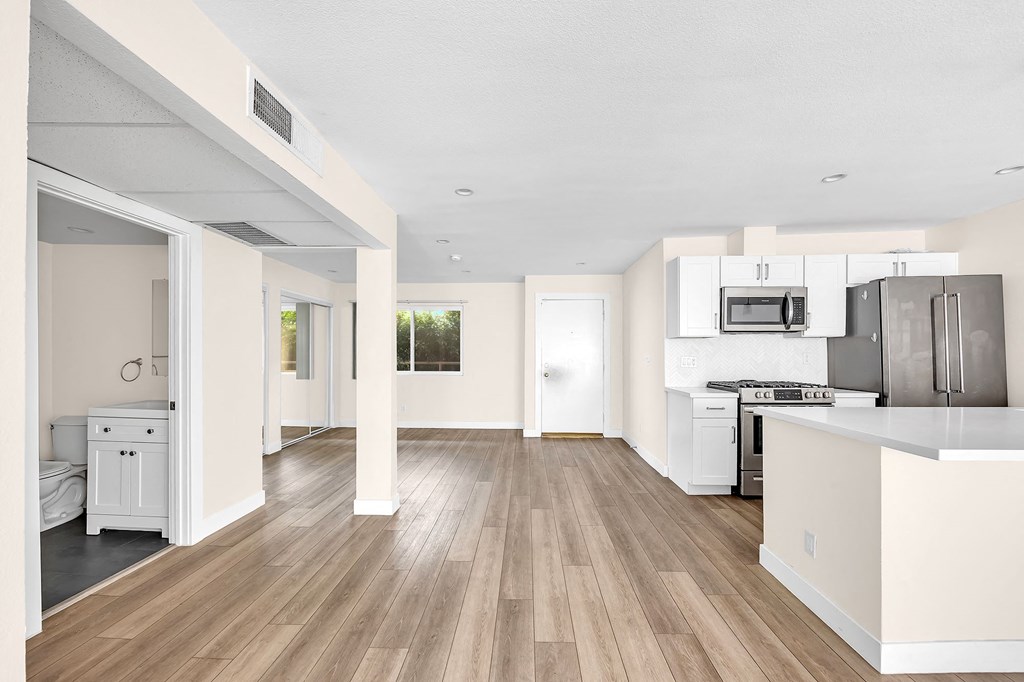 A kitchen with white cabinets and a wooden floor.