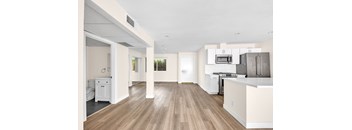 A kitchen with white cabinets and a wooden floor.