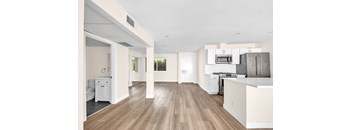 A kitchen with white cabinets and a wooden floor.
