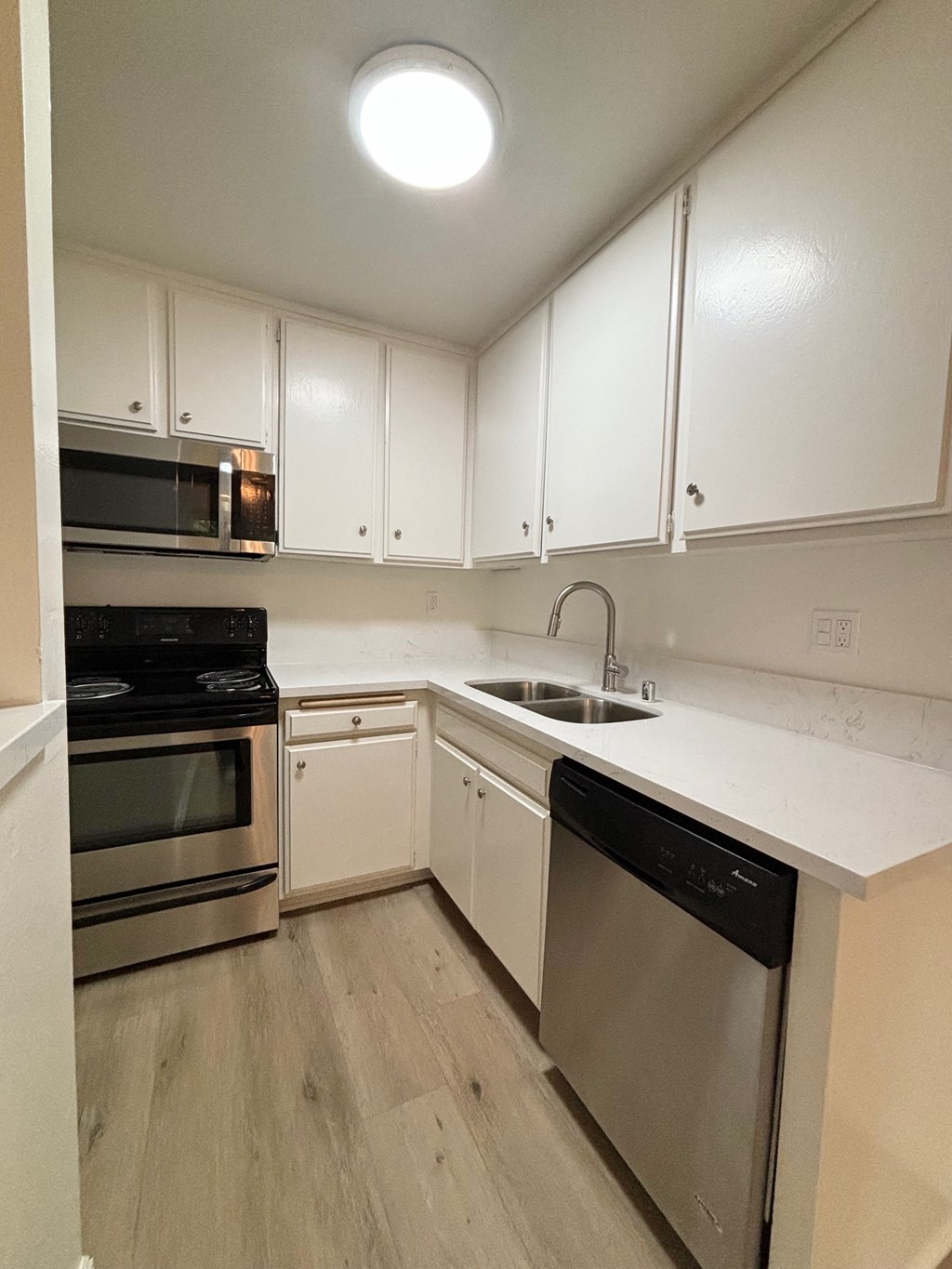 an empty kitchen with white cabinets and stainless steel appliances