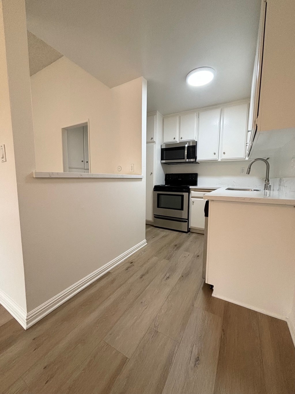 an empty kitchen with white cabinets and a wood floor