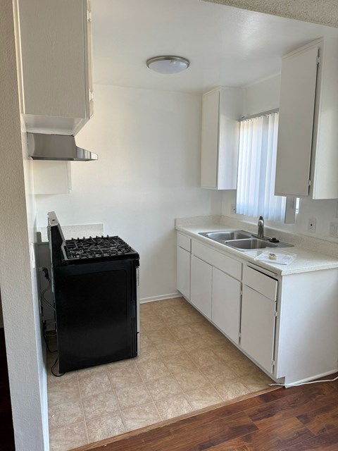 A kitchen with a black dishwasher and white cabinets.