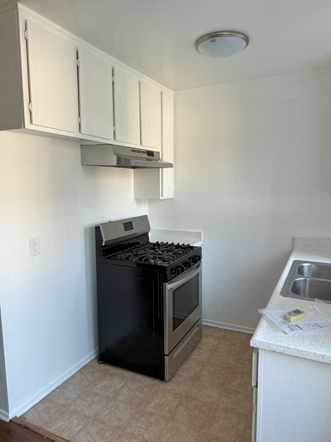 A kitchen with a black stove top oven and white cabinets.