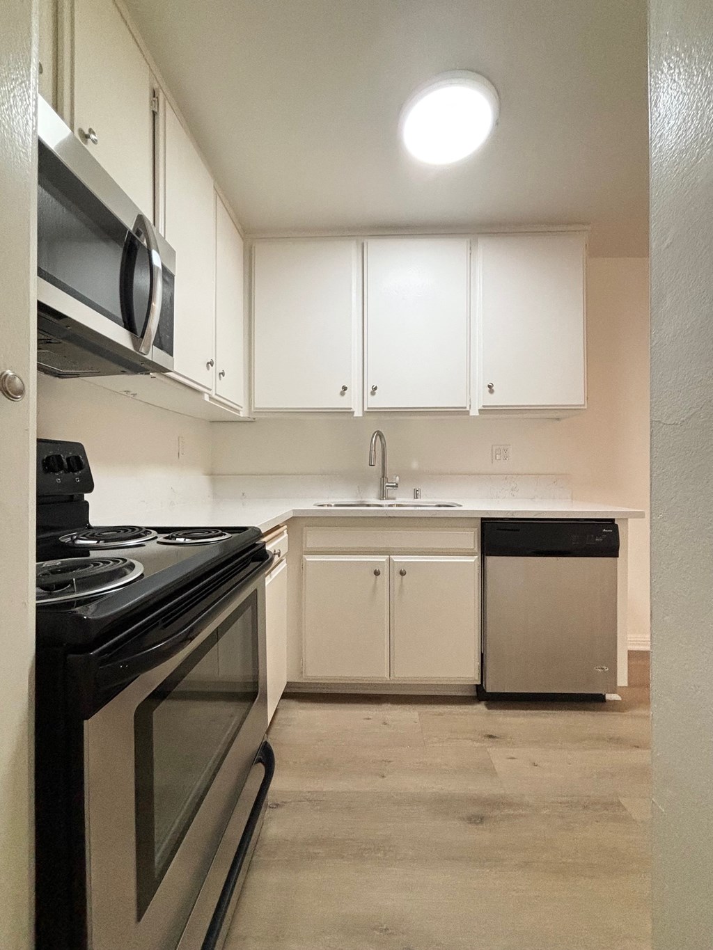 an empty kitchen with white cabinets and a stove and sink