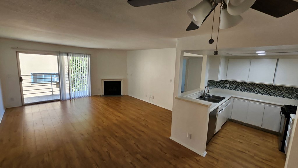 A room with a ceiling fan and wooden flooring.
