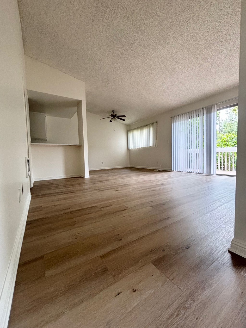 an empty living room with wood flooring and a ceiling fan