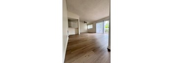 an empty living room with wood flooring and a ceiling fan