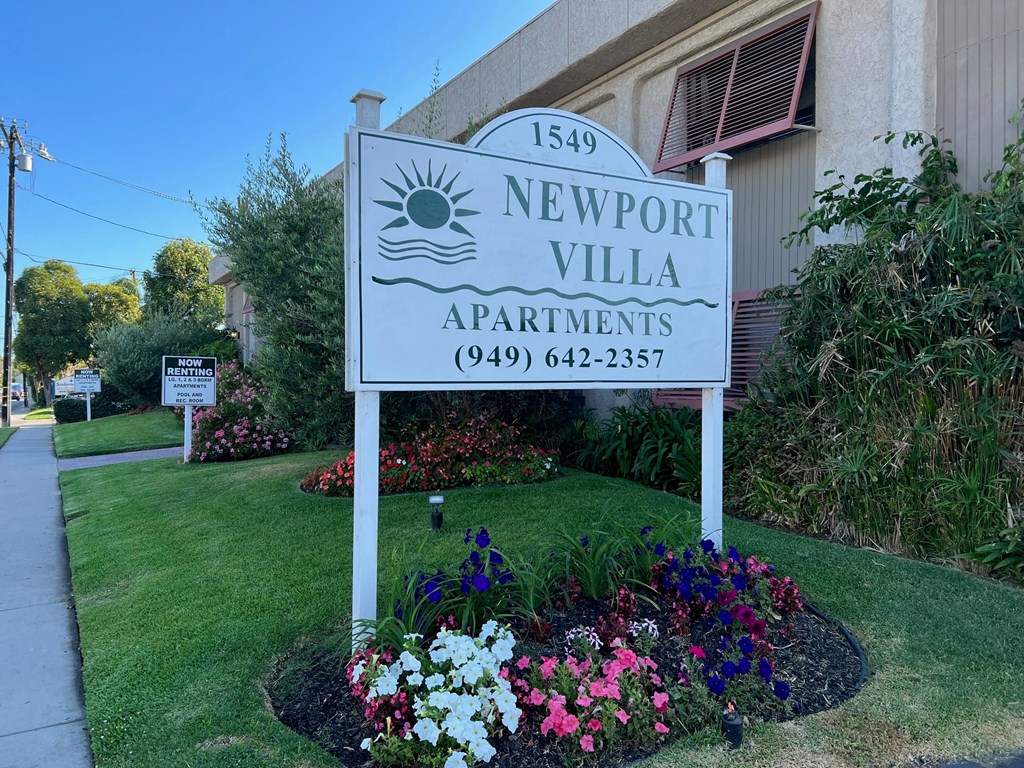a sign apartments in front of some flowers