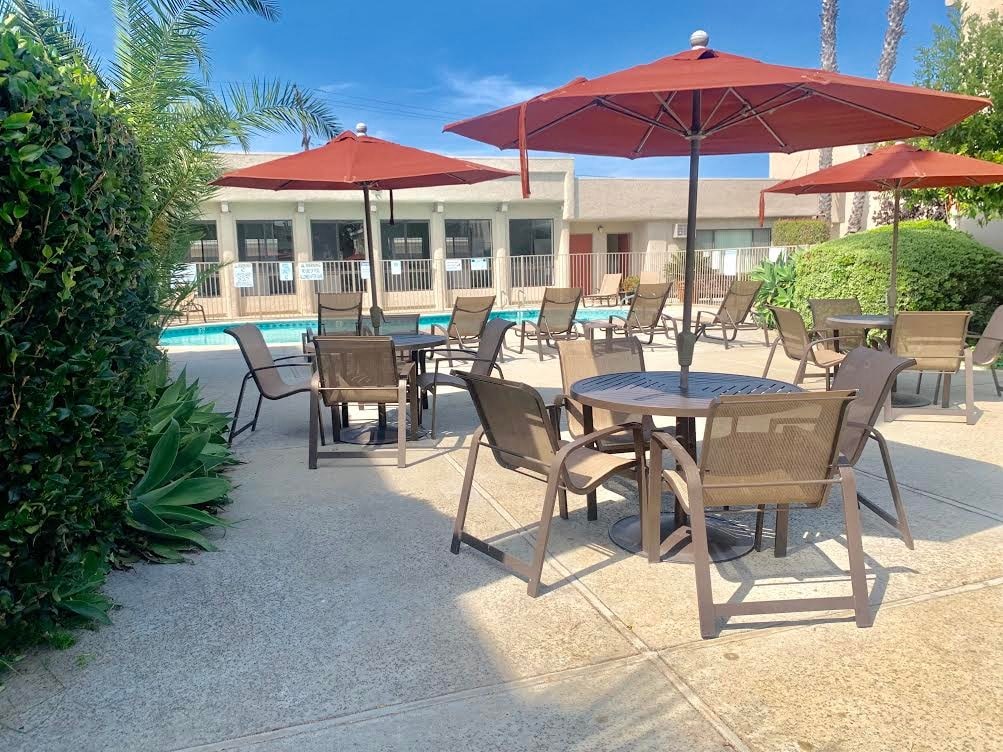 a patio with tables and umbrellas next to a pool