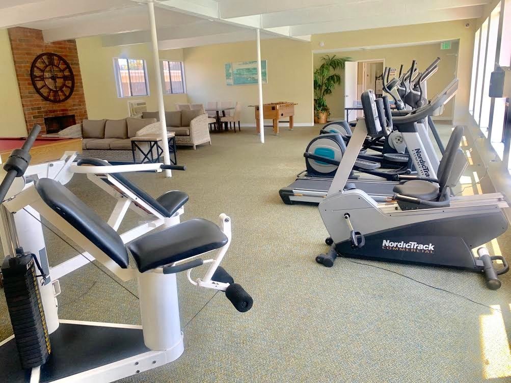 a gym with several machines and a couch in a living room