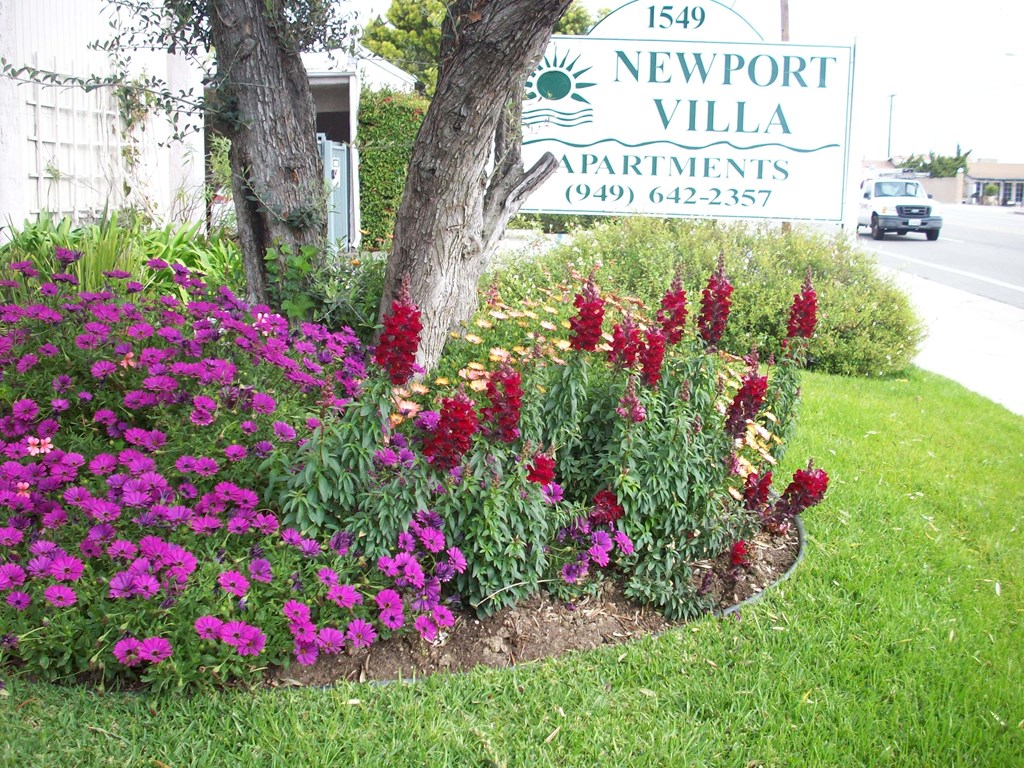 a flower garden in front of a sign apartments