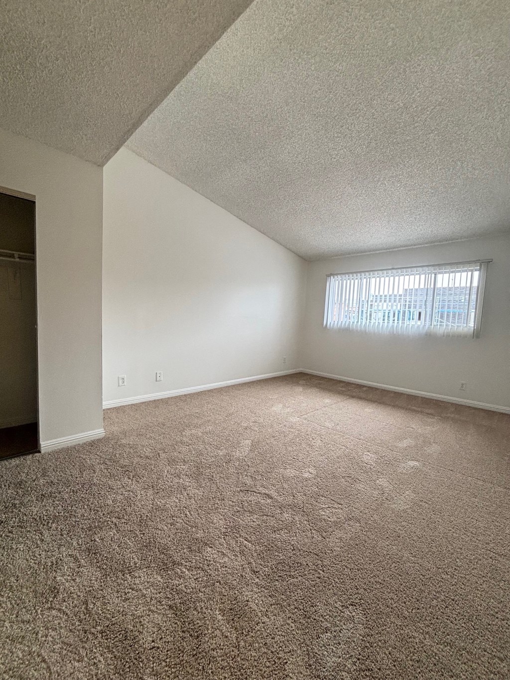 an empty living room with carpet and a window