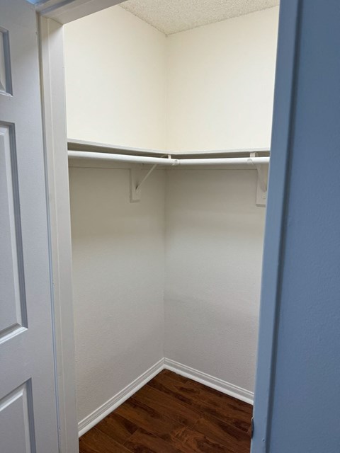 A white closet with a white door and a white shelf.