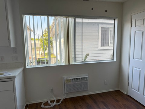 A room with a window and a white wall.