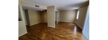 A room with wooden flooring and a window on the right side.