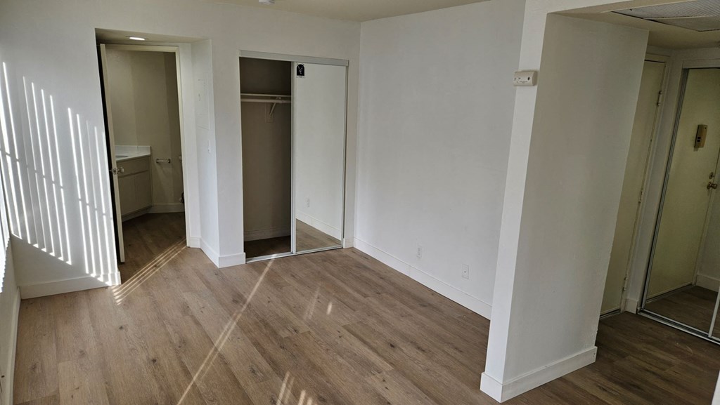 A room with wooden floors and white walls with two doors.