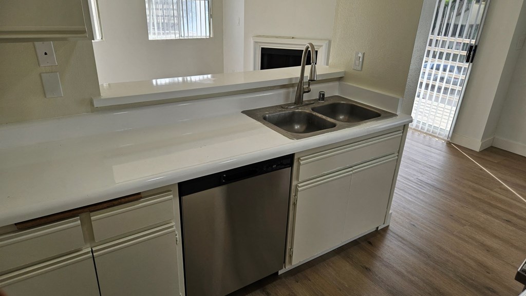 A kitchen with a white counter top and a stainless steel dishwasher.