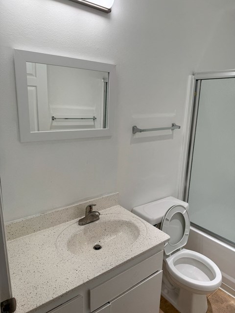 A white bathroom with a sink, toilet, and mirror.