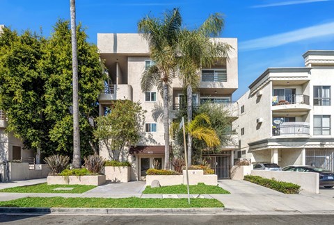 A modern residential building with a well-maintained lawn and trees.