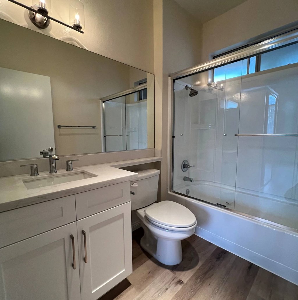 A white toilet sits in a bathroom next to a sink and a shower.