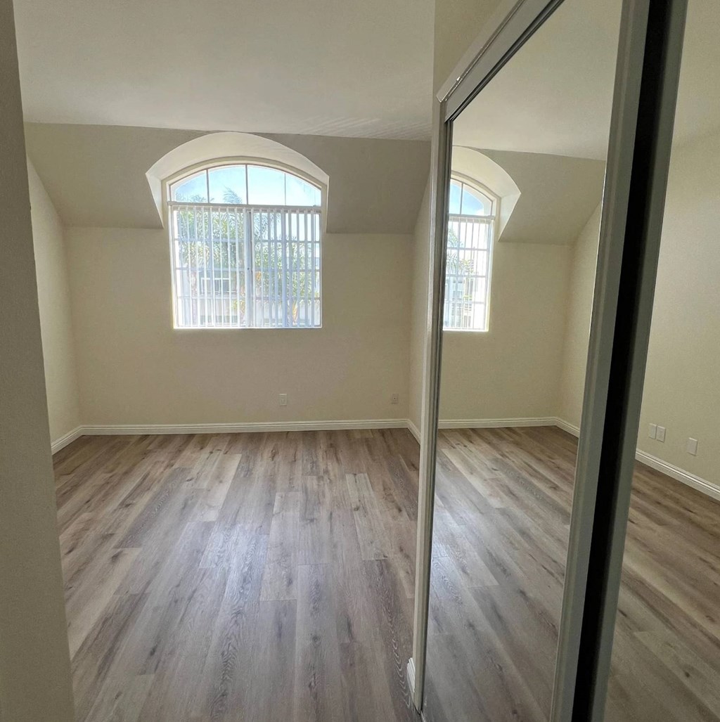 A room with wooden floors and a large arched window.