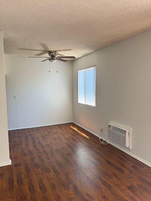 A room with a ceiling fan and a window with a white frame.