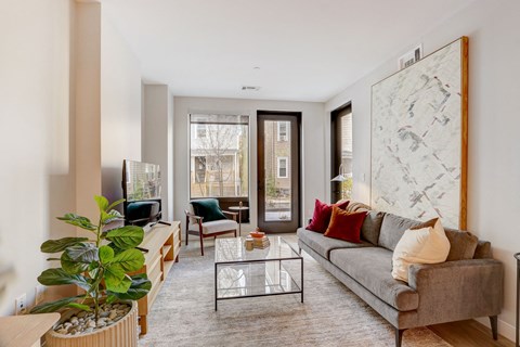 A living room with a grey couch, a coffee table, and a large painting on the wall.