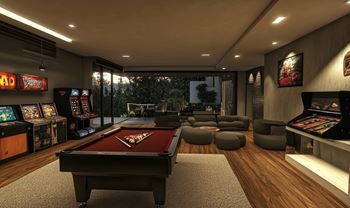 A room with a pool table, arcade games, and a bar.