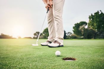 A person is playing golf on a sunny day.
